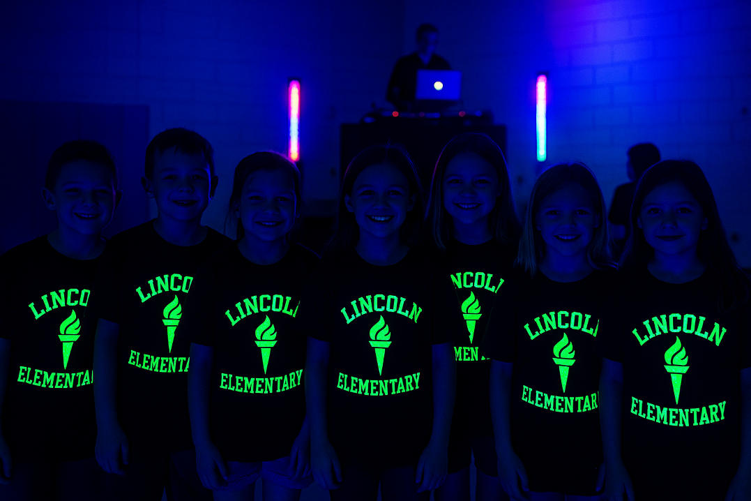 A group of students wearing glow-in-the-dark shirts at a school event.
